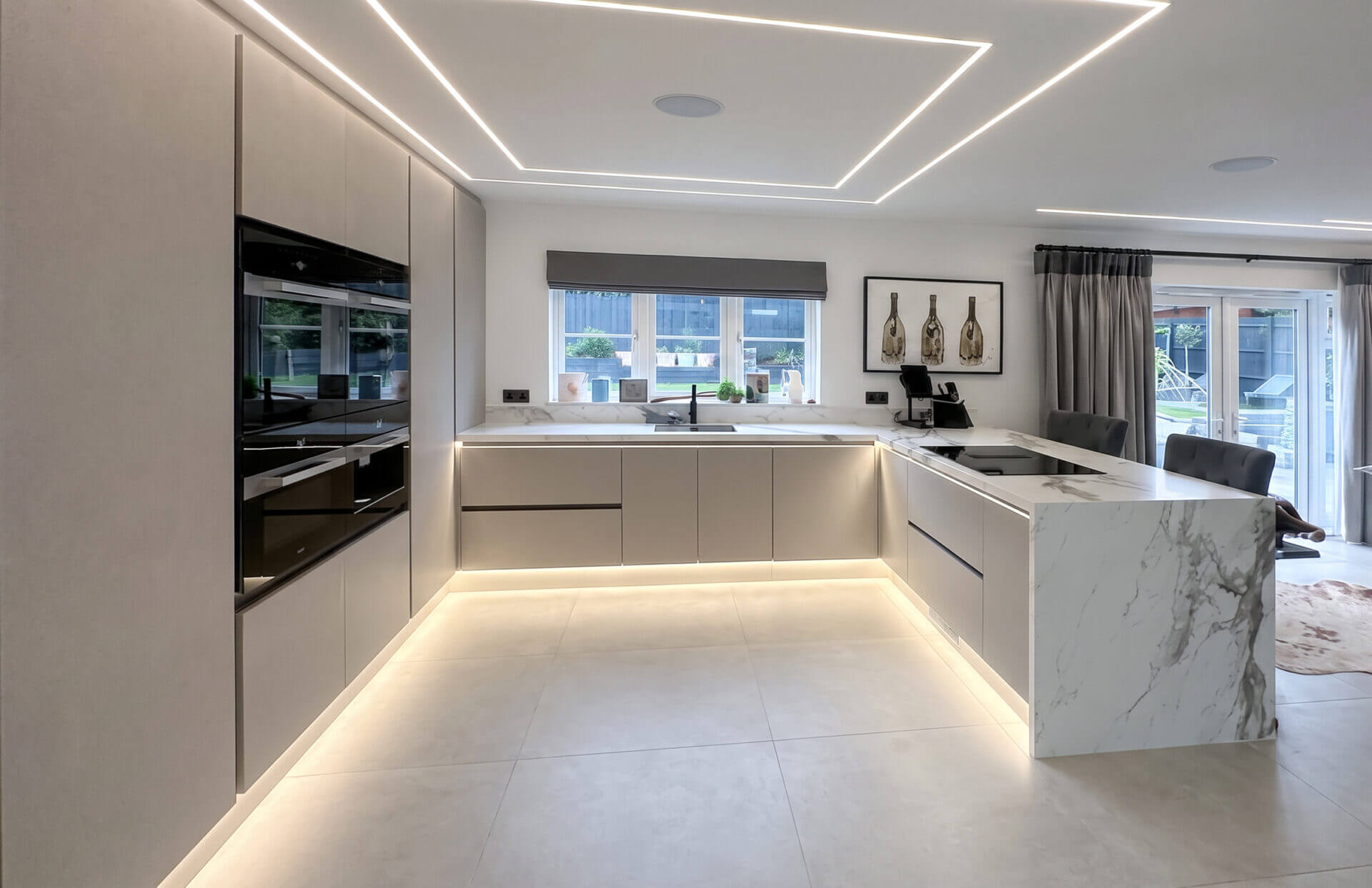 Handleless cream kitchen with a marble-effect island and LED strip lighting